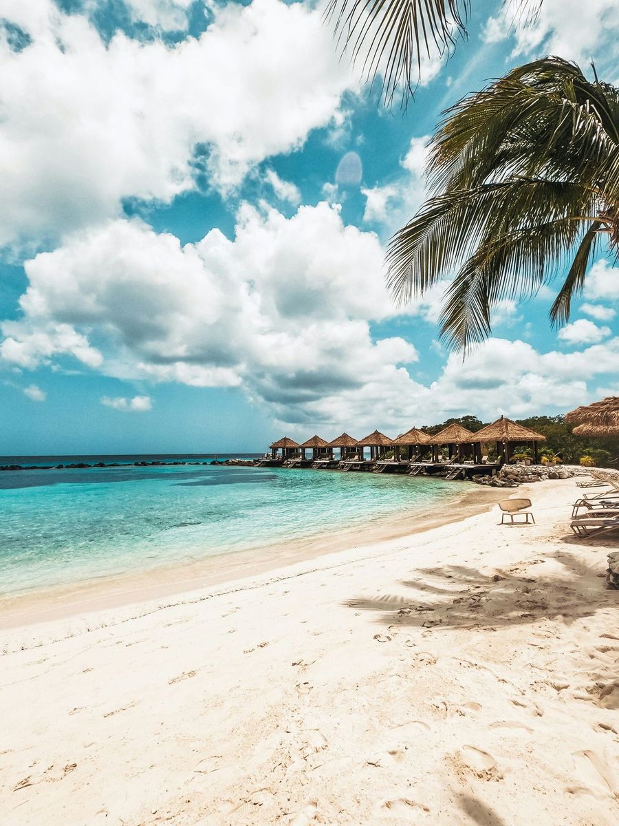 A white-sand beach in Aruba with beach cabanas over clear turquoise water