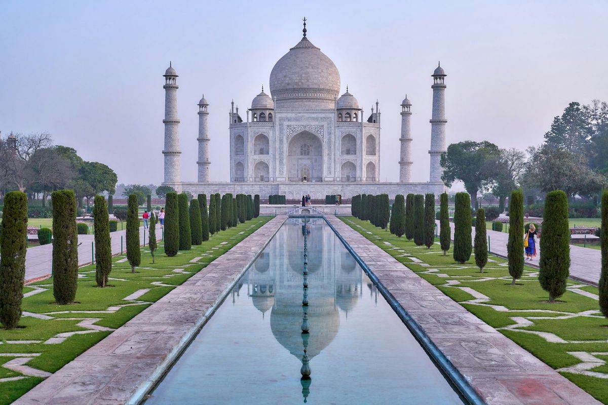 The Taj Mahal reflected in a long pool, with cypress-lined gardens