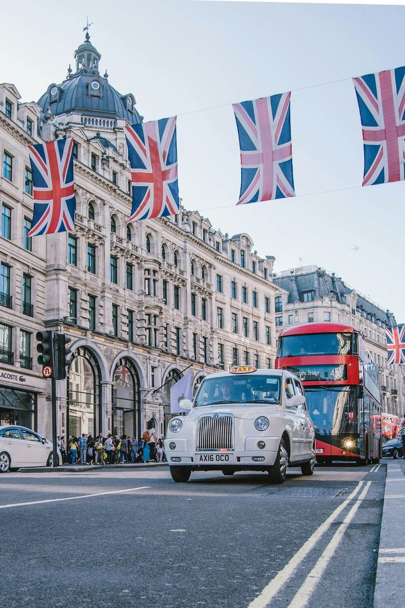 A London taxi and red double-decker bus beneath Union Jack flags on Regent Street