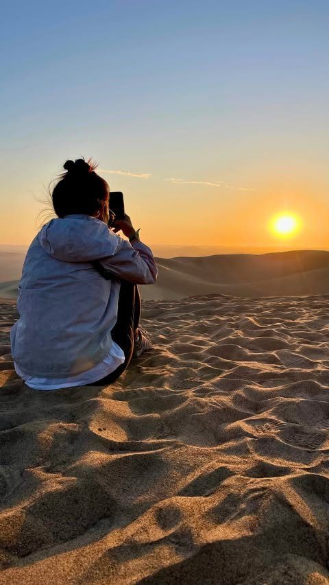 Someone photographing the sunset over the dunes in Peru